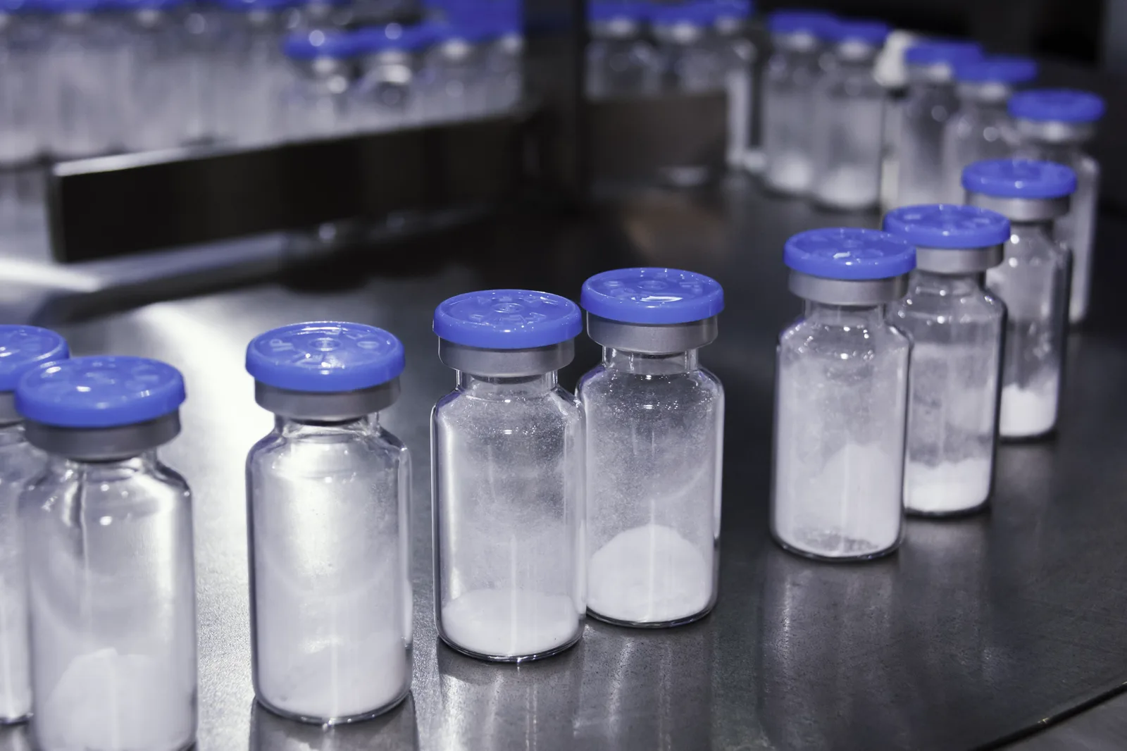 Lyophilized research vials with blue caps on a production line